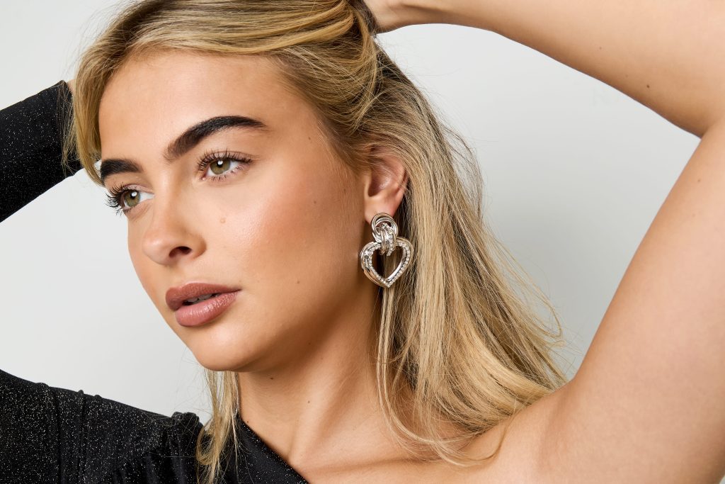 Silberne gedrehte Herz-Ohrringe am Modell - trendige Statement-Schmuck für Frauen, hypoallergene Ohrringe