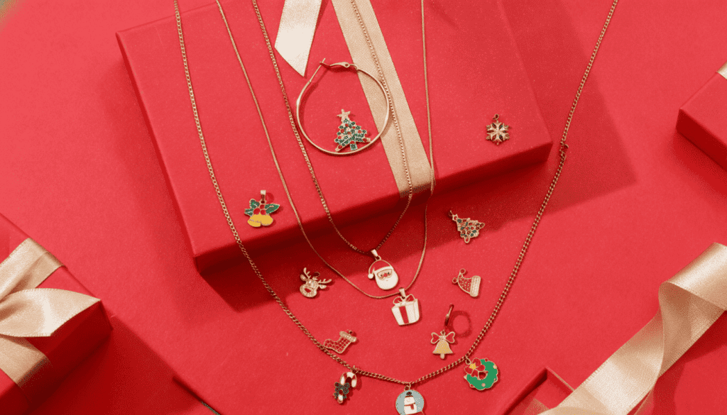A set of festive Christmas jewelry (necklaces, charms, hoop earrings) with Santa, Christmas tree, and snowflake motifs, displayed on red gift boxes.