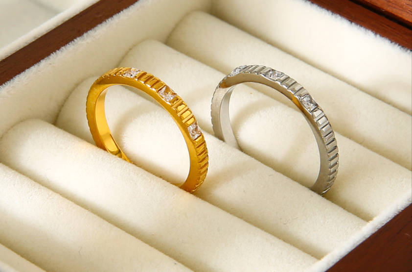Gold and silver textured band rings with small diamonds, displayed in a soft-lined jewelry box